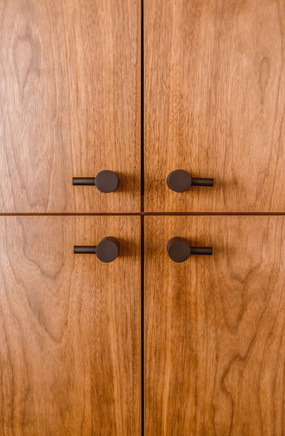 Four light brown wooden cabinet doors with dark handles.