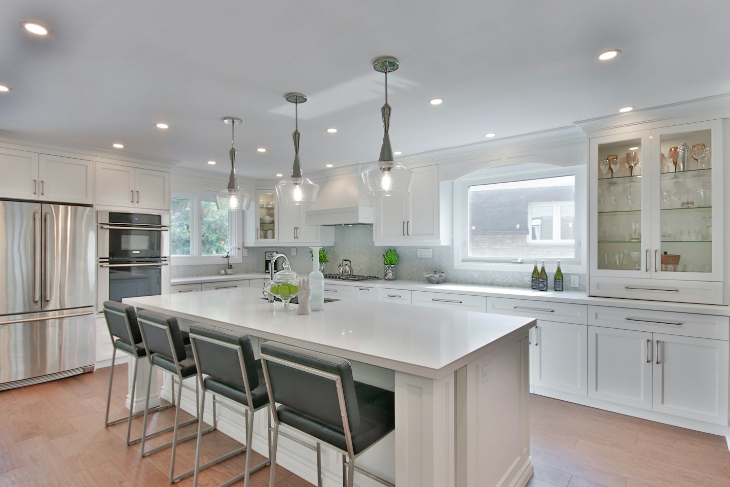Modern kitchen with white island and bar stools.