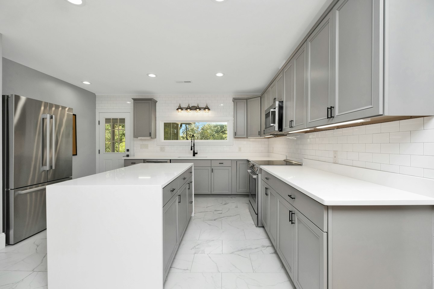 A modern grey and white kitchen with a large island.