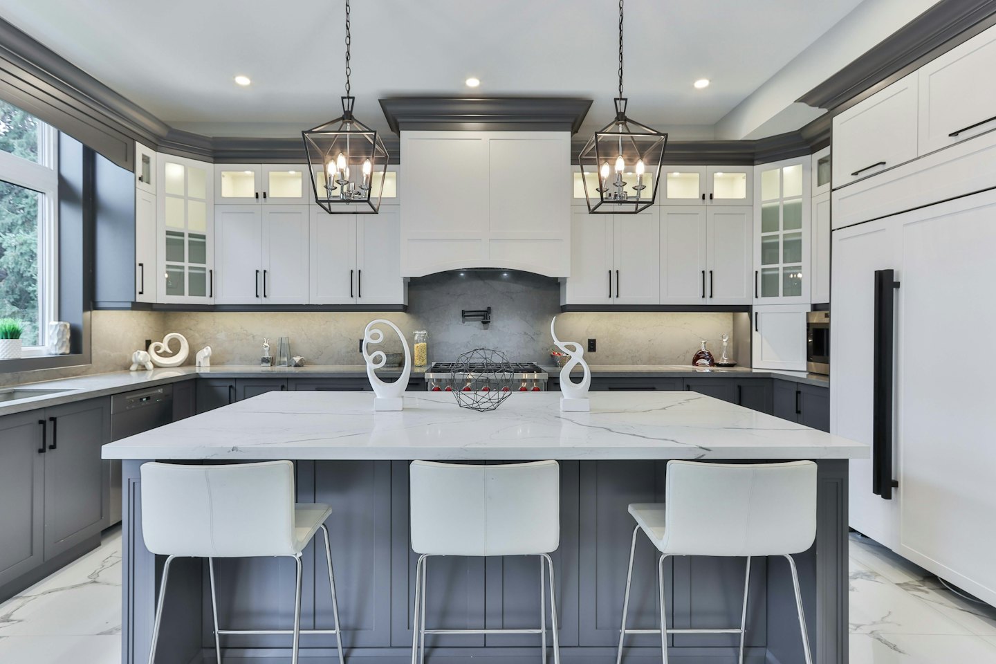Modern kitchen island with marble top and three bar stools.